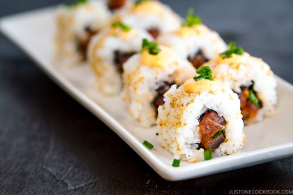 spicy tuna roll garnish with sesame seeds and topped with spicy mayo served on a dish