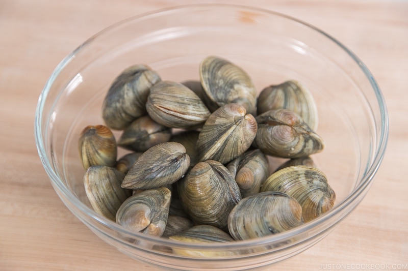 A glass bowl containing manila clams.