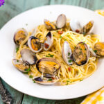 A white plate containing clam pasta.