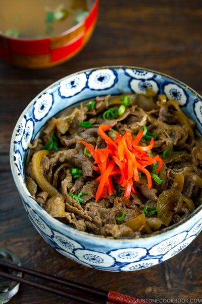 A bowl containing simmered beef over steamed rice.