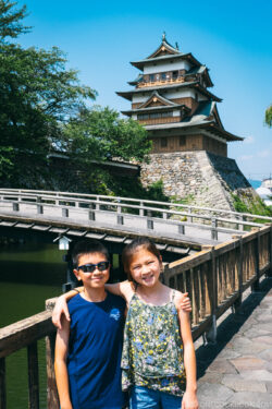 two children in front of a bridge with Takashima Castle in the back