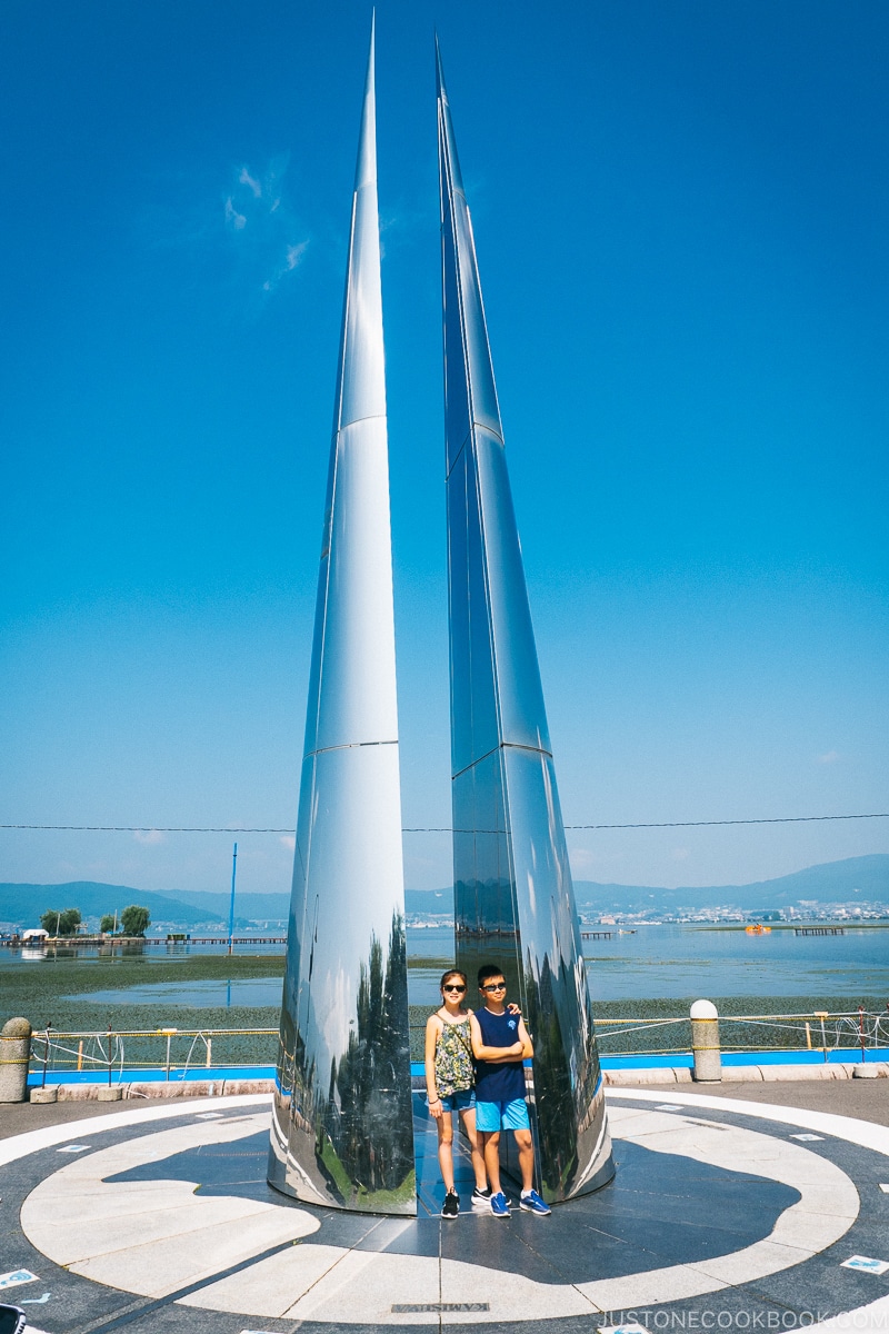 kids standing next to metal sculpture at Lake Suwa