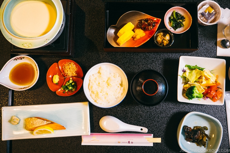 Japanese breakfast with rice, fish, soup, on top of a black tray