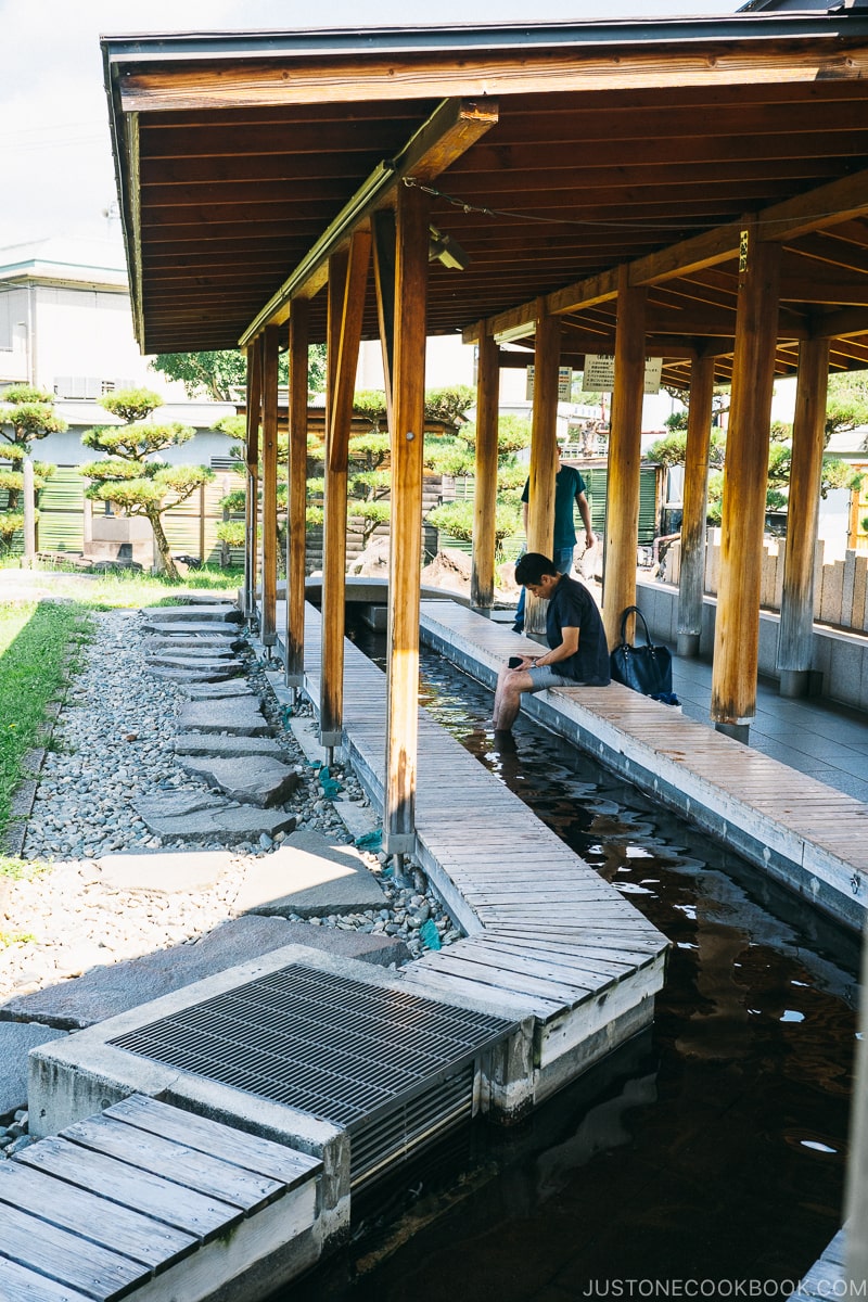 men soaking his feet in hot spring under a covered roof