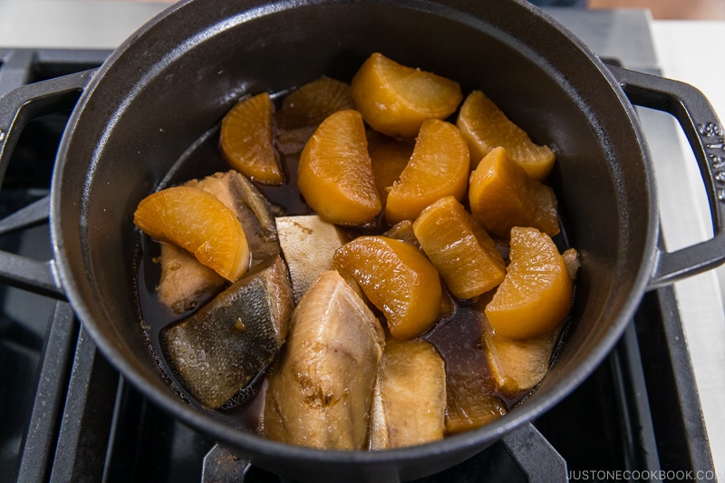 hamachi and daikon cooking in a metal pot