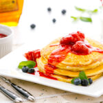 A dish containing Buttermilk Pancakes with strawberry compote.