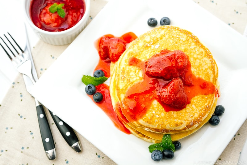 A dish containing Buttermilk Pancakes with strawberry compote.