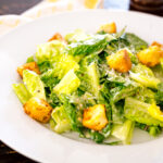 A white plate containing Caesar Salad with Homemade Croutons.