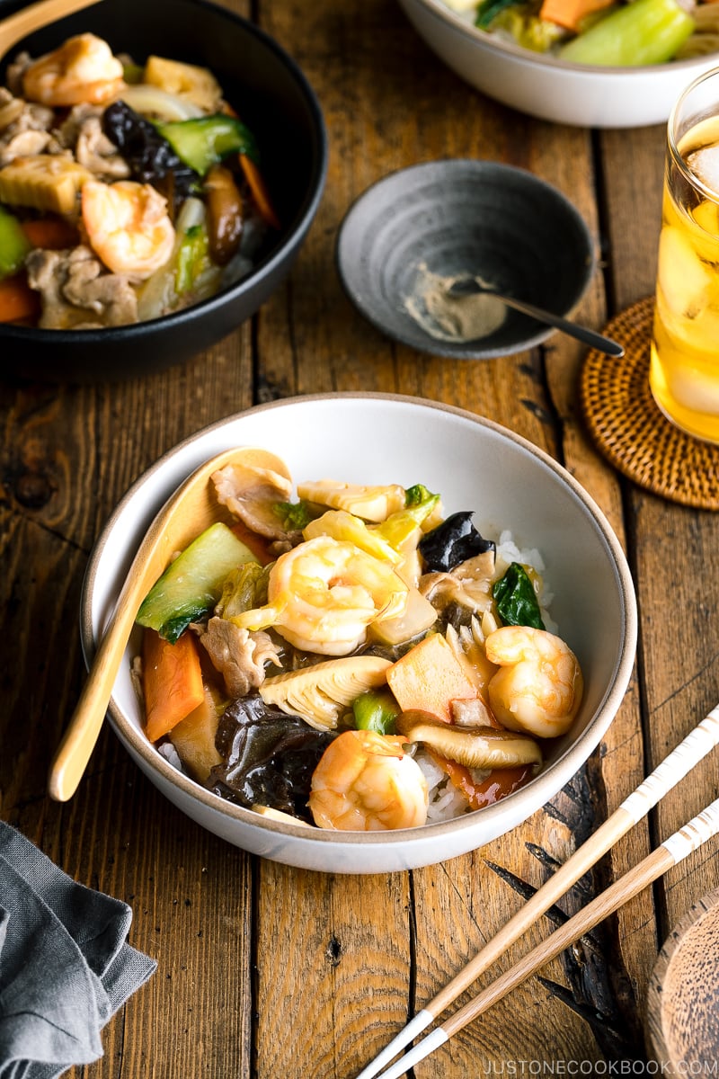 A white bowl containing Chukadon (Seafood and Vegetable Stir Fry Over Rice).