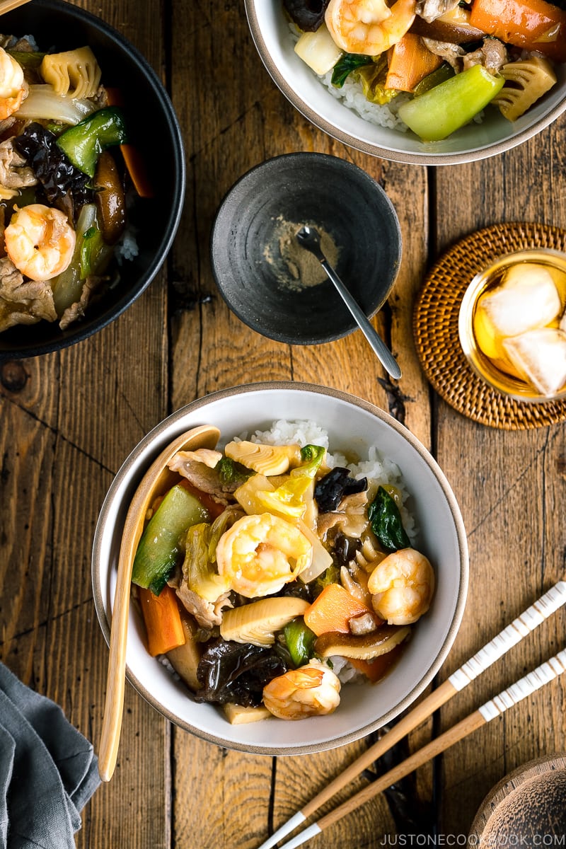 A white bowl containing Chukadon (Seafood and Vegetable Stir Fry Over Rice).