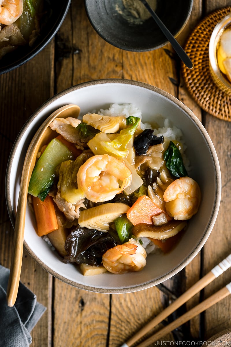 A white bowl containing Chukadon (Seafood and Vegetable Stir Fry Over Rice).