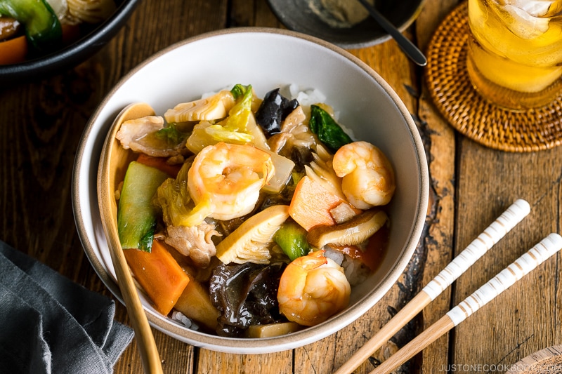 A white bowl containing Chukadon (Seafood and Vegetable Stir Fry Over Rice).