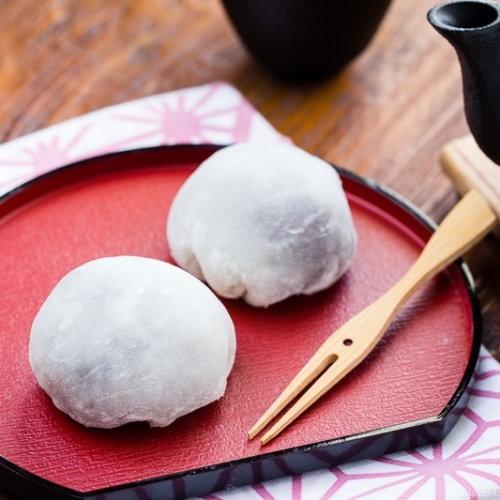 A Japanese red plate containing daifuku mochi.