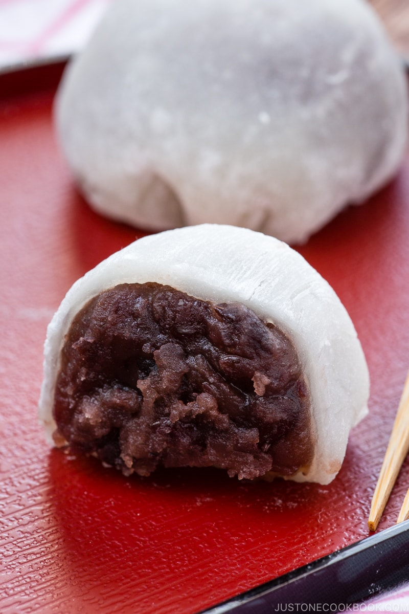 A Japanese red plate containing daifuku mochi (sliced in half).