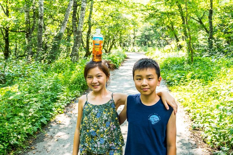 two children on a path surrounded by trees and shurbs