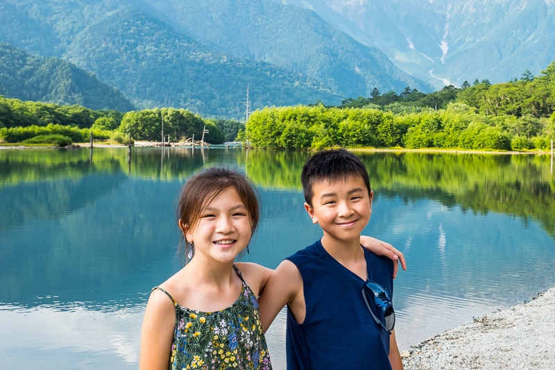 boy and girls standing next to Taisho Pond with mountain scenery in the back