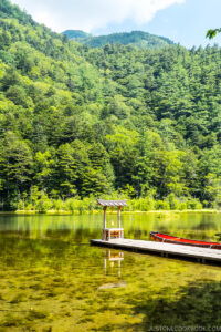 a praying altar at the end of the dock in the middle of a large pond with mountain in the back
