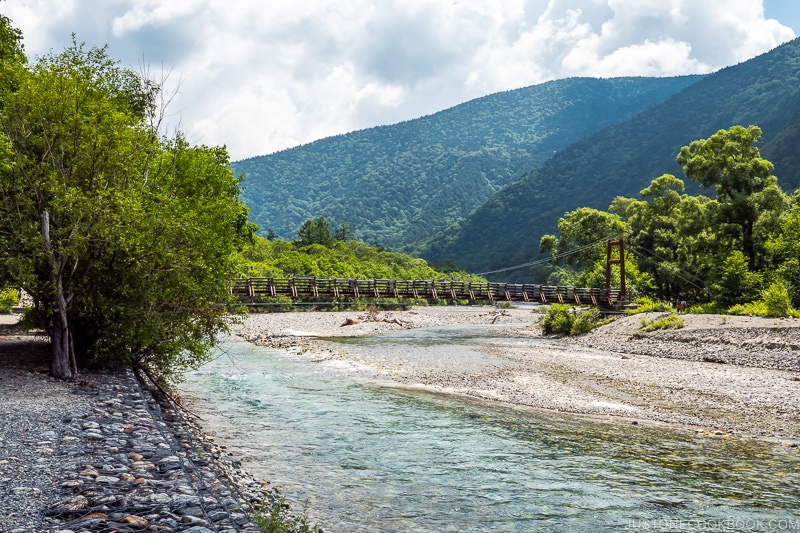 Myojin Bridge crossing Azusa River with rocky shores and mountain scenery in the background
