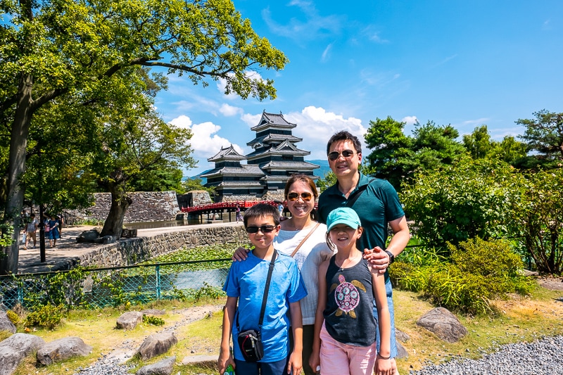 a family standing in front of Matsumoto Castle