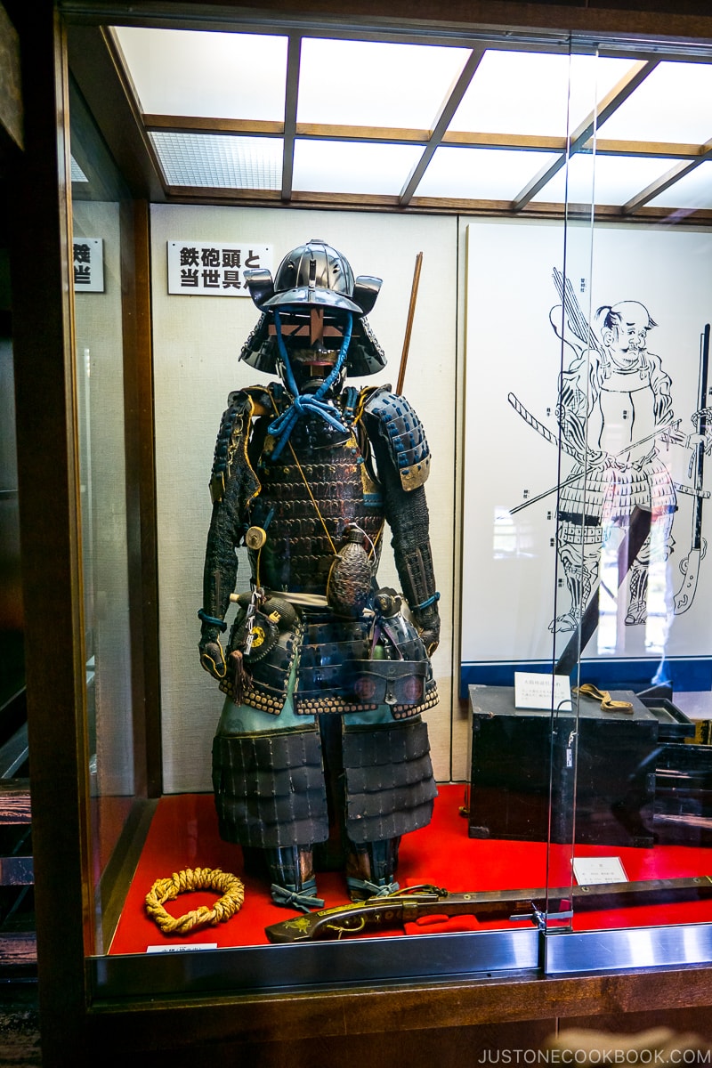 antique guns and armors in a glass display case