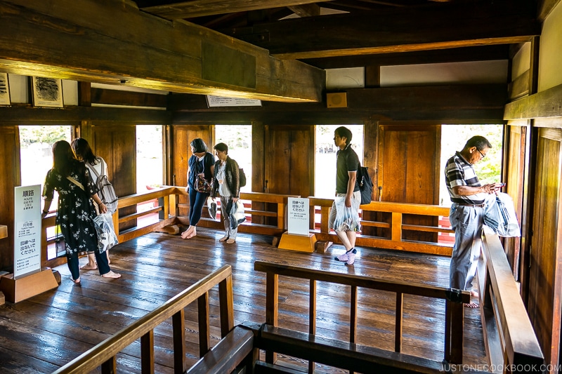 visitors on a wood viewing platform looking out windows