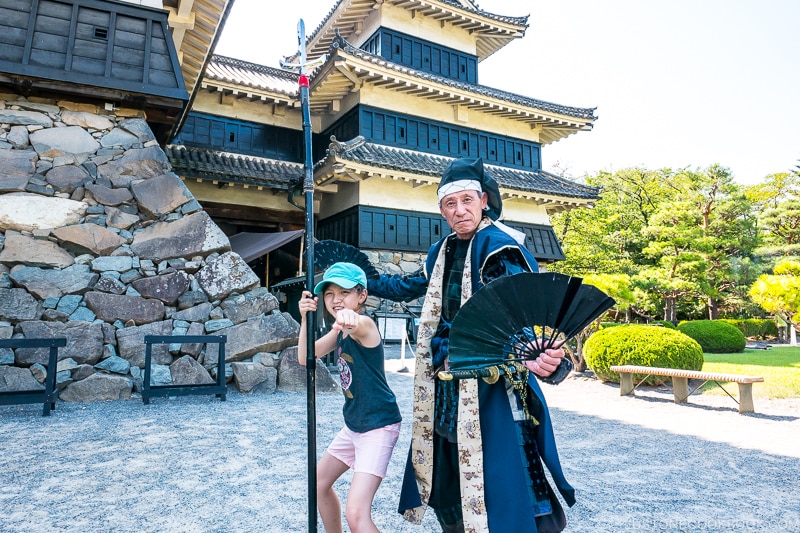 girl standing next to a man in costume next to Matsumoto Castle