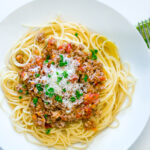 A white plate containing Spaghetti Meat Sauce.