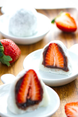 White plates containing strawberry mochi cut in half.