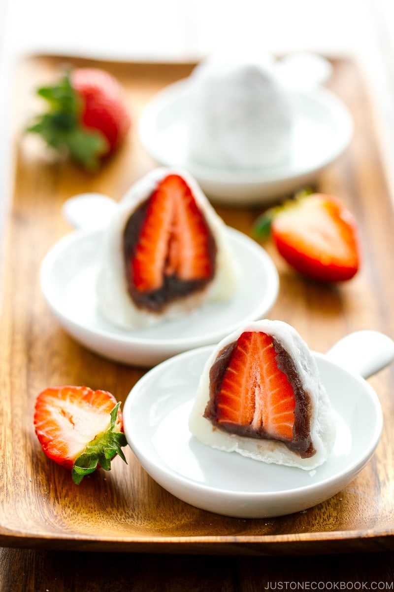 White plates containing strawberry mochi cut in half.