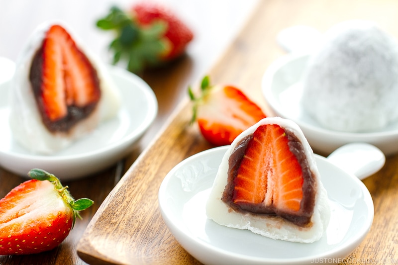 White plates containing strawberry mochi cut in half.