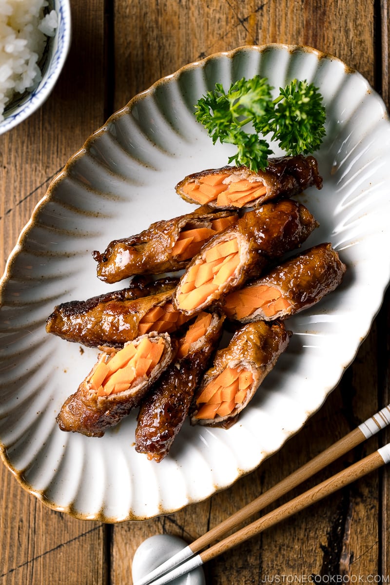 An oval ceramic plate containing Carrot Beef Rolls garnished with parley.