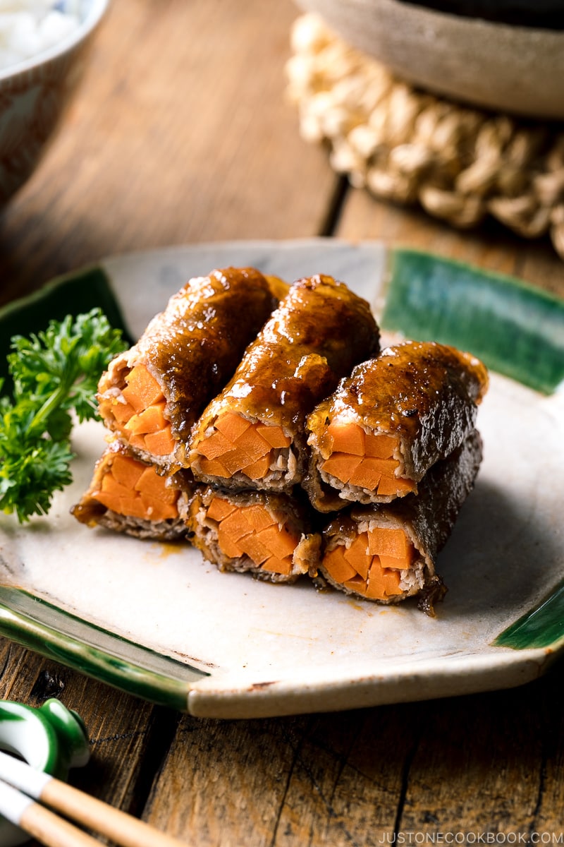 An oval ceramic plate containing Carrot Beef Rolls garnished with parley.