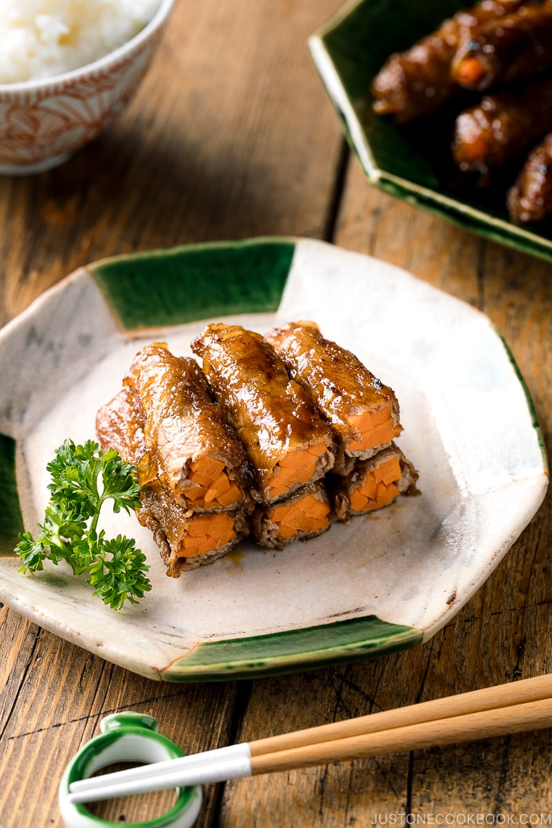 An oval ceramic plate containing Carrot Beef Rolls garnished with parley.