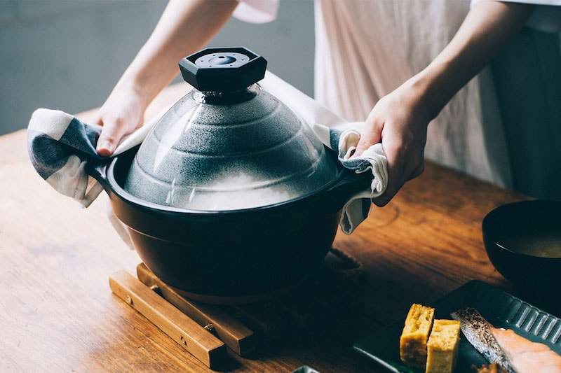 a person holding the handles of Hario rice cooker