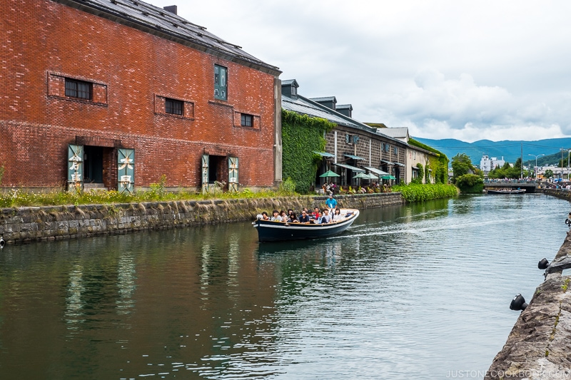 a boat cruising down Otaru Canal with warehouses in the background