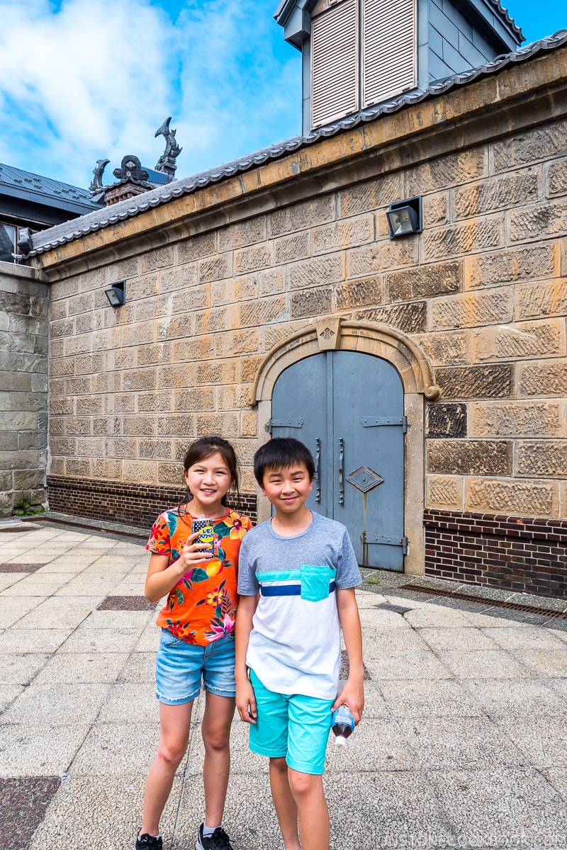 two children in a courtyard in front of a stonewall