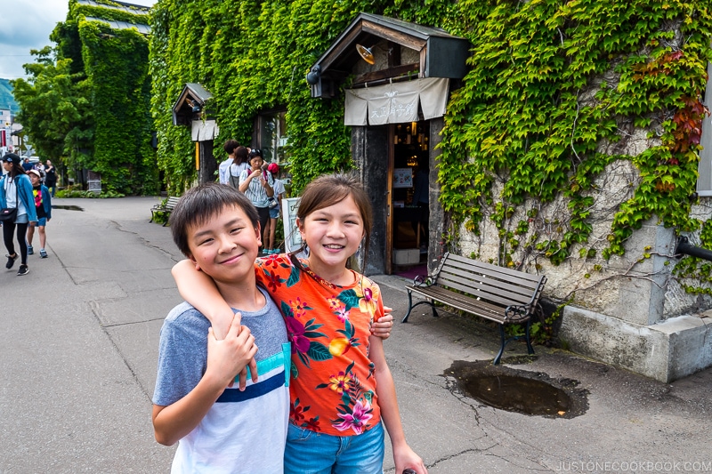 two children in front of stone building covered in ivy