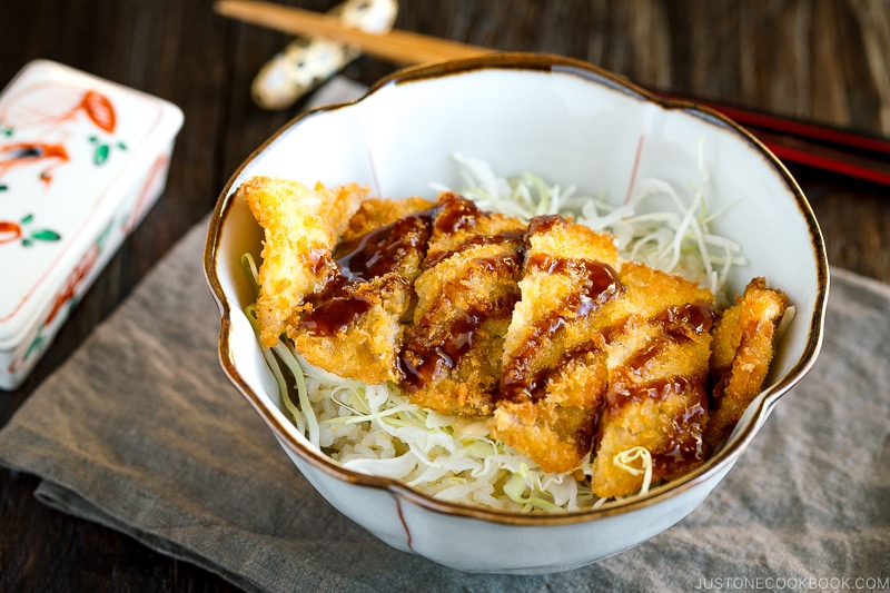A donburi bowl containing crispy tonkatsu over rice topped with tonkatsu sauce.