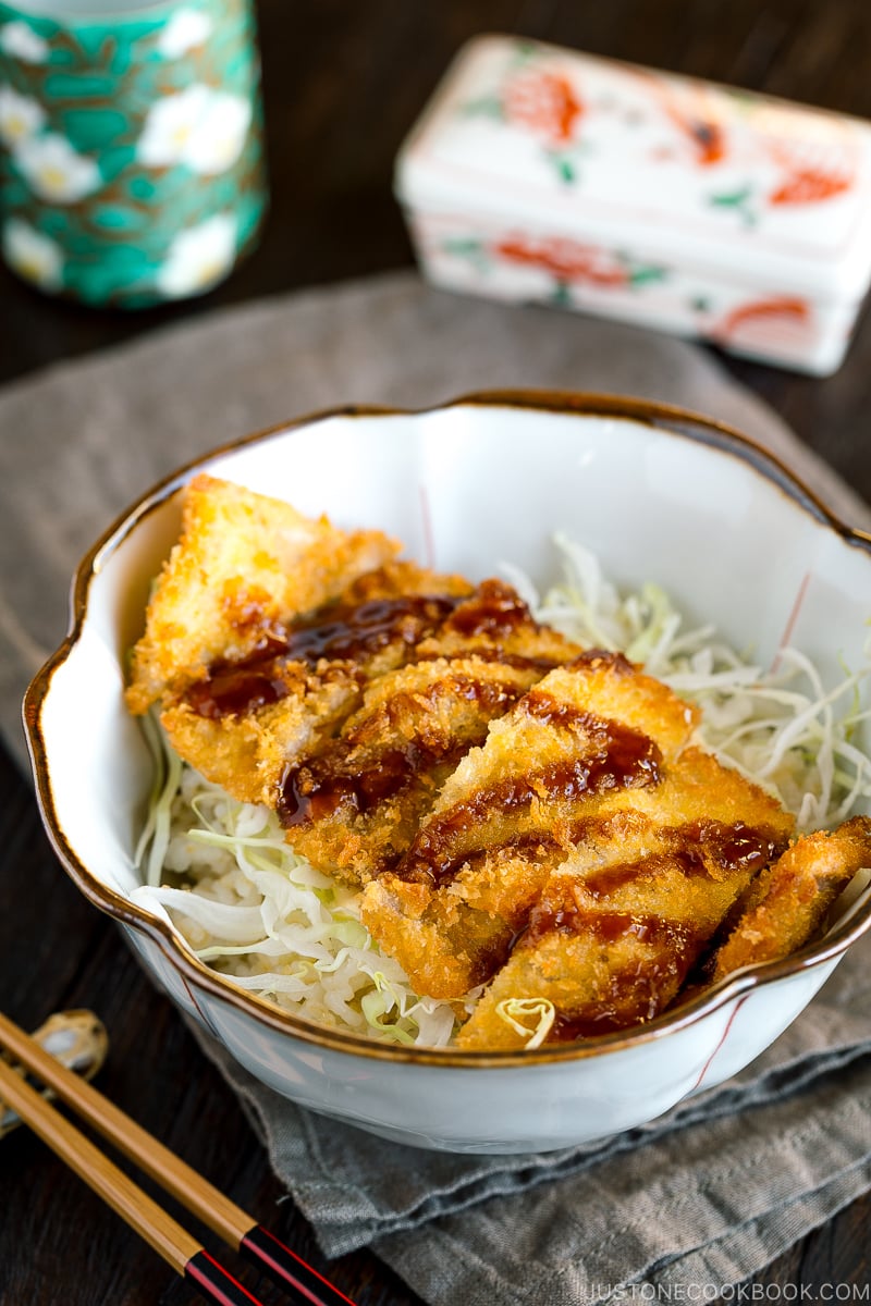 A donburi bowl containing crispy tonkatsu over rice topped with tonkatsu sauce.