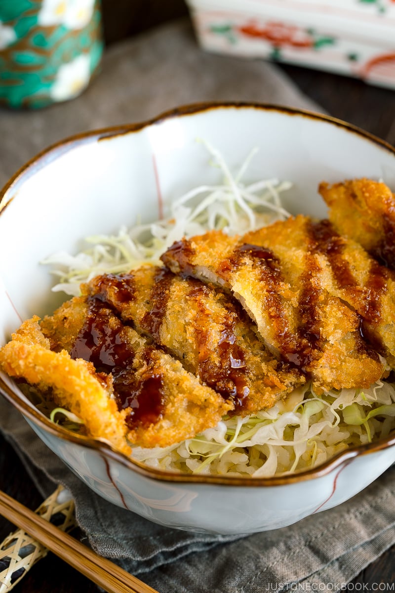 A donburi bowl containing crispy tonkatsu over rice topped with tonkatsu sauce.