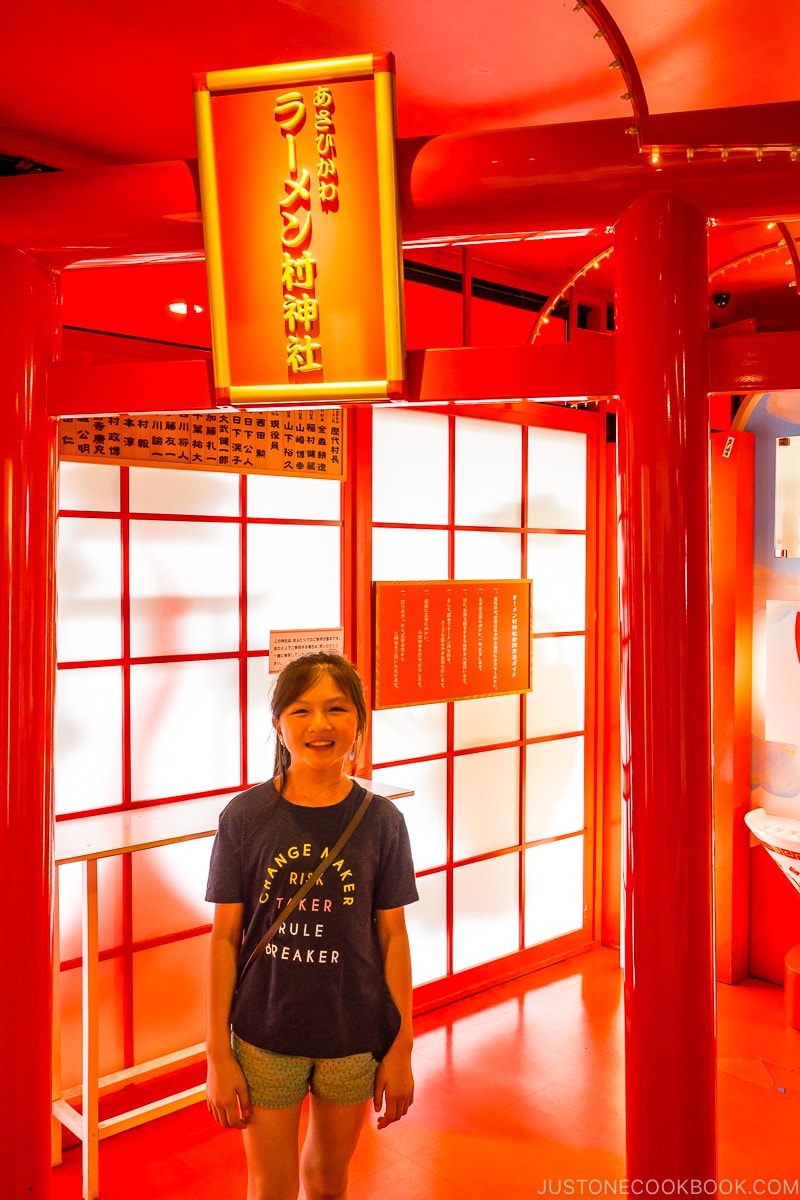 girl standing under torii gate at ramen village shrine