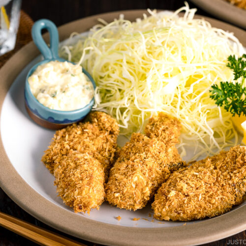 A plate containing fried oyster (kaki furai) along with shredded cabbage and tartar sauce.