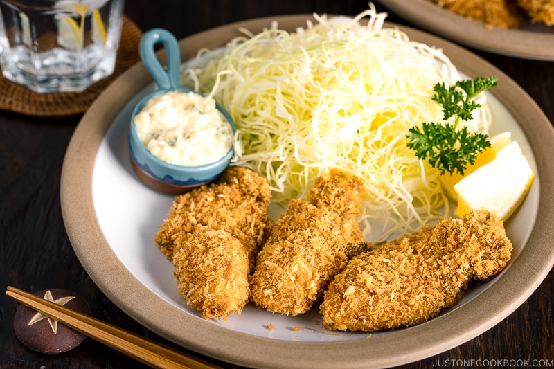 A plate containing fried oyster (kaki furai) along with shredded cabbage and tartar sauce.