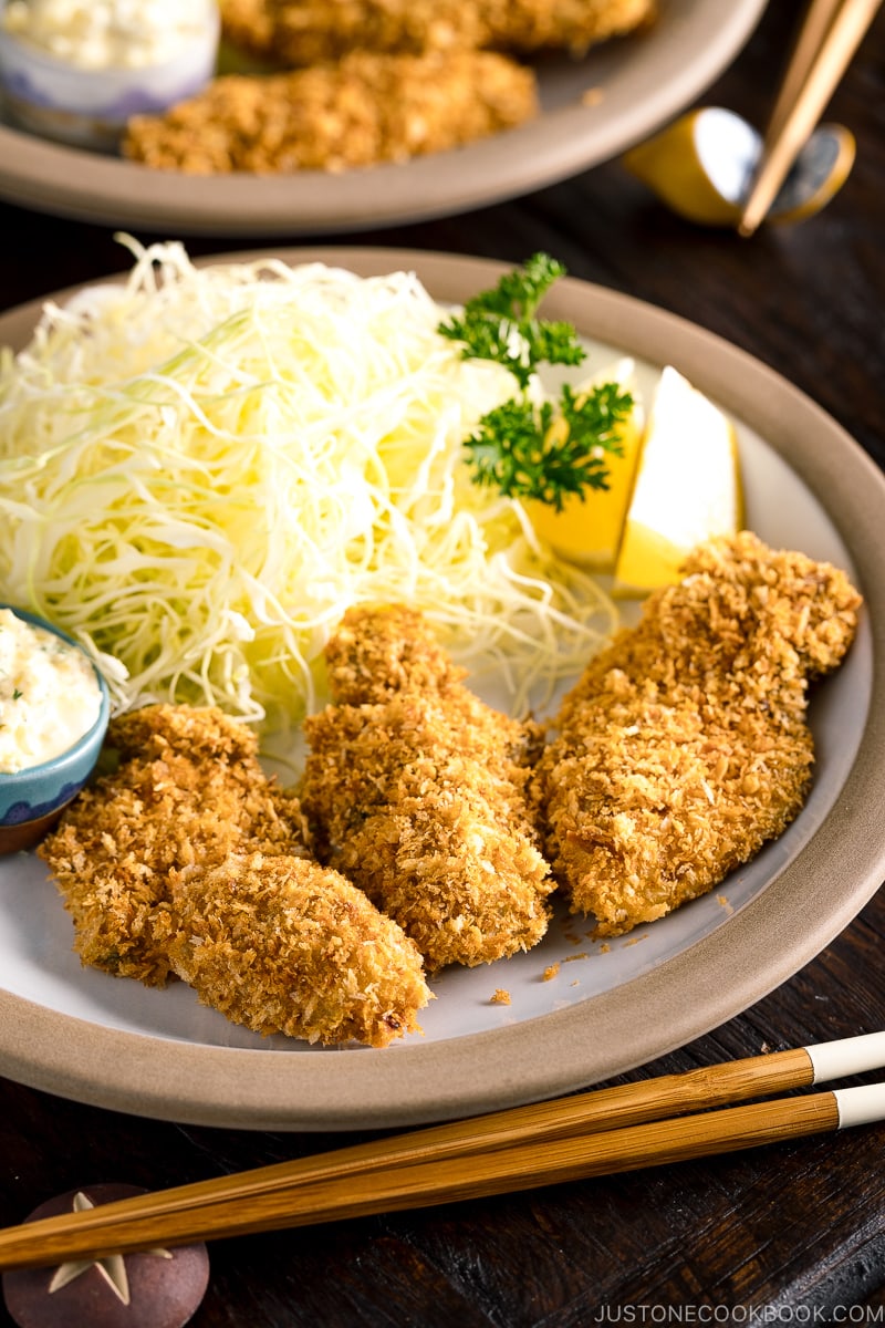 A plate containing fried oyster (kaki furai) along with shredded cabbage and tartar sauce.