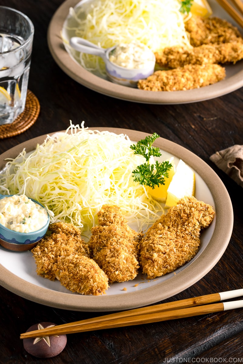 A plate containing fried oyster (kaki furai) along with shredded cabbage and tartar sauce.