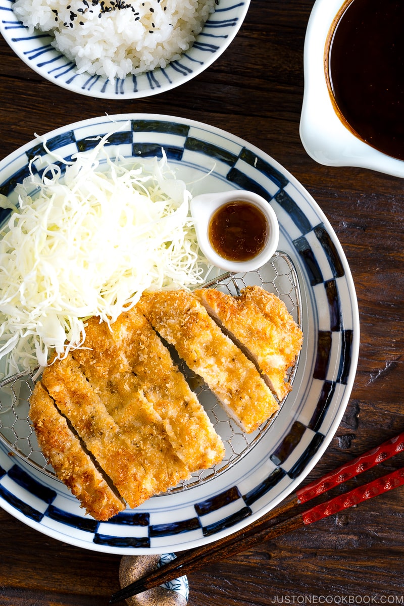 A plate containing Tonkatsu, shredded cabbage, and a small bowl of miso sauce.