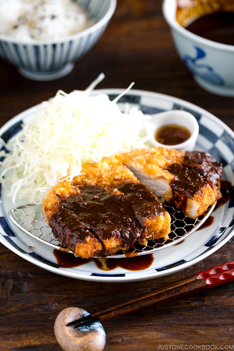 A plate containing Tonkatsu, shredded cabbage, and a small bowl of miso sauce.