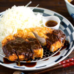 A plate containing Tonkatsu, shredded cabbage, and a small bowl of miso sauce.