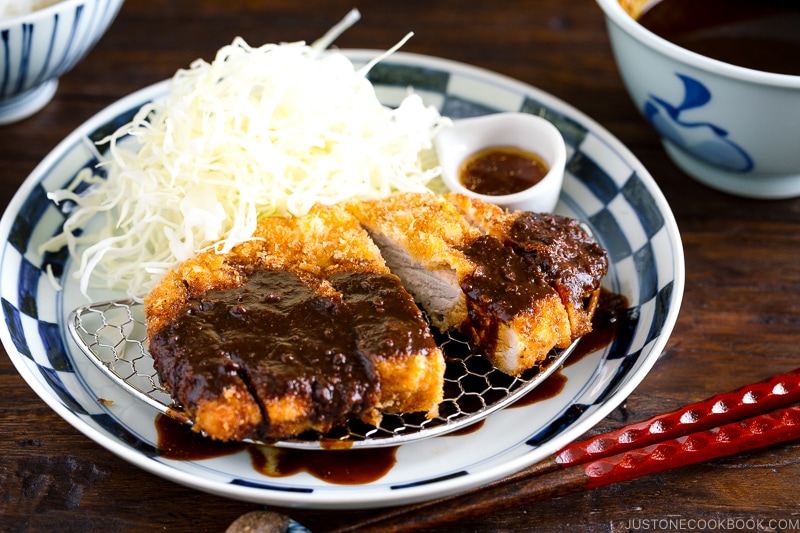 A plate containing Tonkatsu, shredded cabbage, and a small bowl of miso sauce.