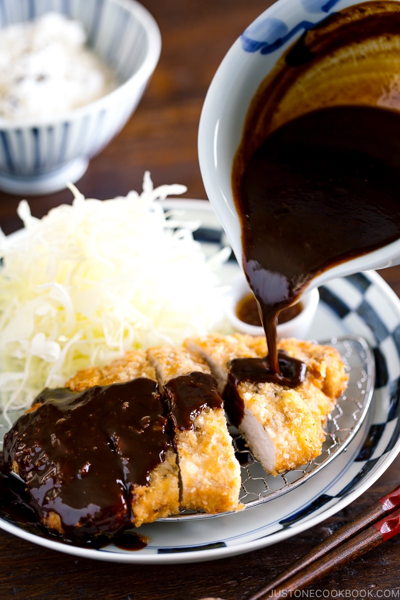 A plate containing Tonkatsu, shredded cabbage, and a small bowl of miso sauce.